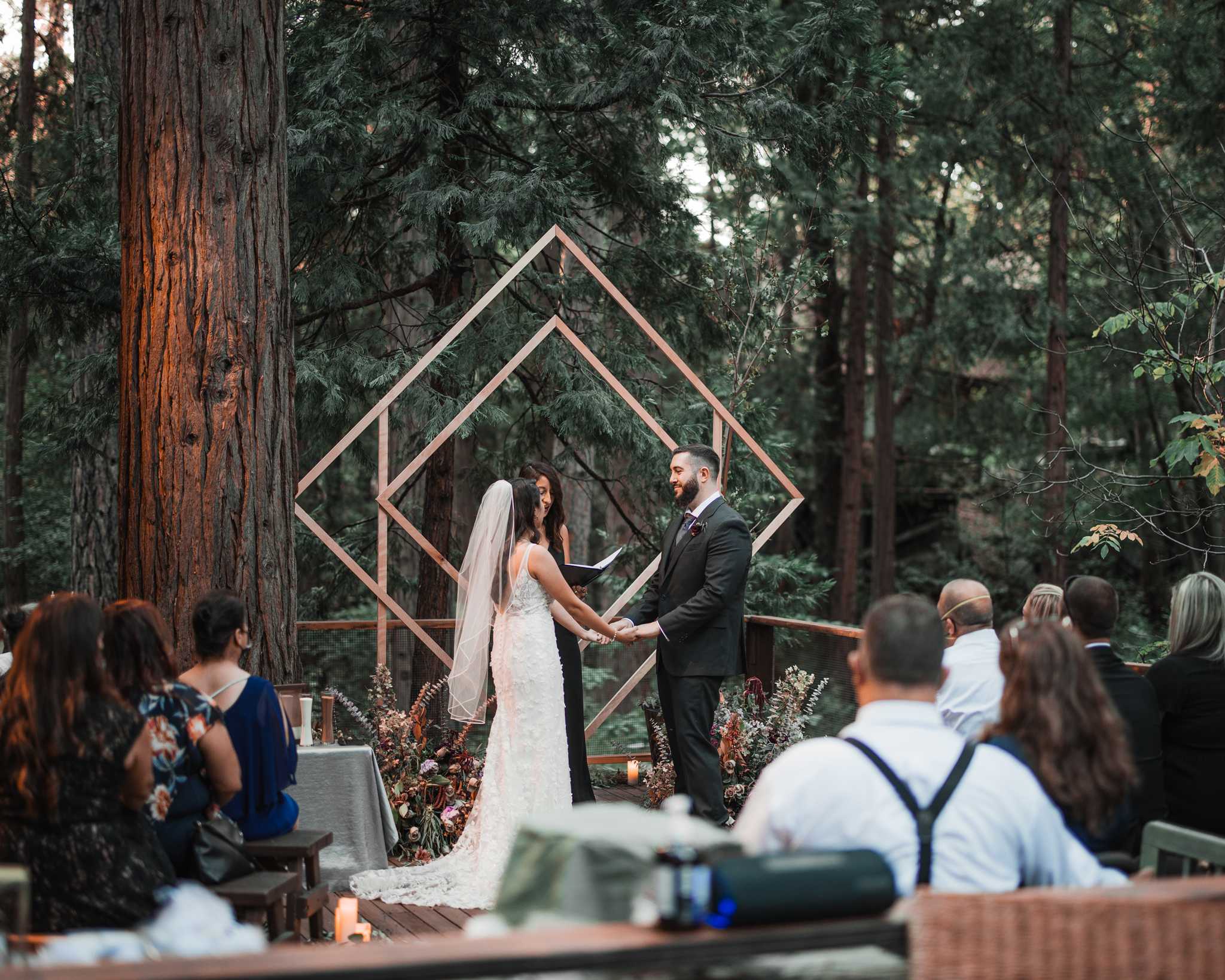 Wide shot of the 16 seated guests viewing Erika and Ken at the alter